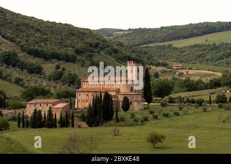 Abbey of Saint Antimo surrounded by hills, olive and cypress trees in the commune of Montalcino, Tuscany, Italy. Stock Photo