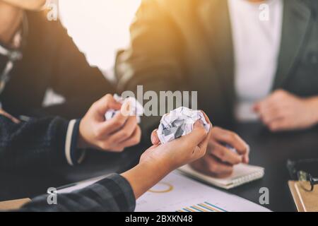 A businessman screwed up papers by hand with laptop, tablet and paper work on the table in a meeting Stock Photo