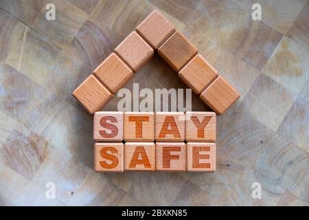 Stay home to stay safe due to Covid-19 coronavirus outbreak pandemic. Concept of self isolation or quarantine message engraved on wooden blocks on woo Stock Photo
