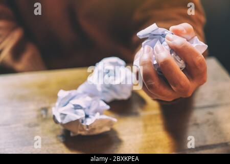A woman screwed up papers by hand on wooden table Stock Photo
