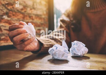 A woman screwed up papers by hand on wooden table Stock Photo