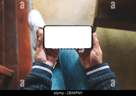 Top view mockup image of hands holding black mobile phone with blank desktop screen Stock Photo