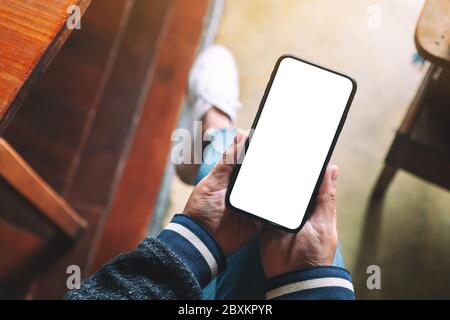 Top view mockup image of hands holding black mobile phone with blank desktop screen Stock Photo