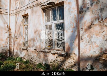 An old, crumbling window with a rusty bars on it. Damaged building. Stock Photo