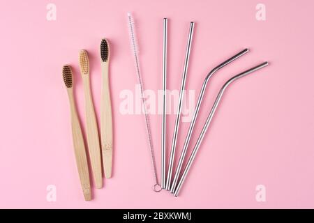 Reusable stainless steel straws and bamboo toothbrushes on pink background, top view. Zero waste and eco friendly concept Stock Photo
