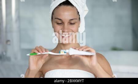 Close up smiling woman applying toothpaste on toothbrush Stock Photo