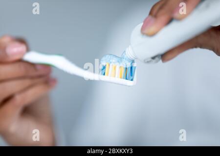 Close up African American woman applying toothpaste on toothbrush Stock Photo