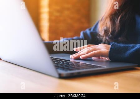 Closeup image of a woman working and touching on laptop touchpad on the table Stock Photo