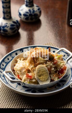 cod fish bacalhau with rice, onions eggs olive oil - portuguese traditional food on wooden table mat and blurred background Stock Photo