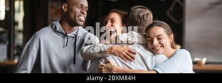 Multi ethnic friends meet mate cuddle him feels happy Stock Photo