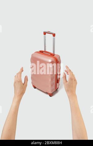 Woman hands try to take travel suitcase on a light grey background. Stock Photo