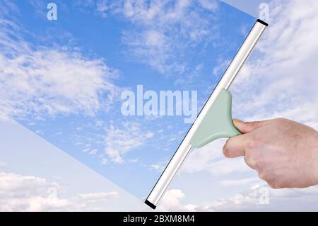Transparency concept. Hand with a squeegee turning dull sky into blue Stock Photo