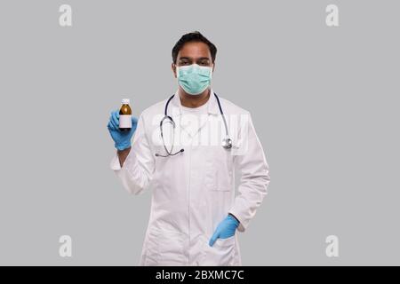 Indian Man Doctor Holding Cough Syrup Wearing Medical Mask and Gloves. Hands Wash Antiseptic. Corona Virus Concept. Isolated Stock Photo