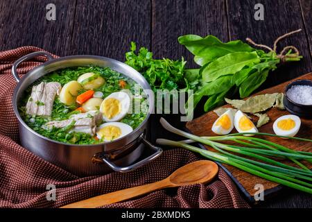 Collard greens classic sorrel soup of fresh sorrel, green onion with pork ribs, young potato, carrot, and boiled eggs, served in a stock pot on a wood Stock Photo