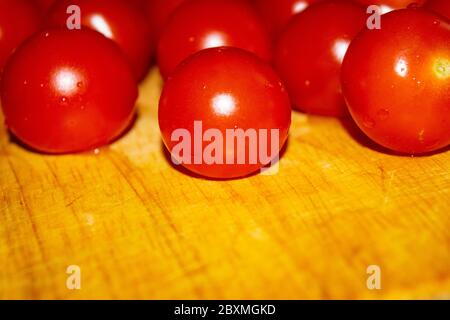 Small red cherry tomatoes on a wooden Board. Close up Stock Photo