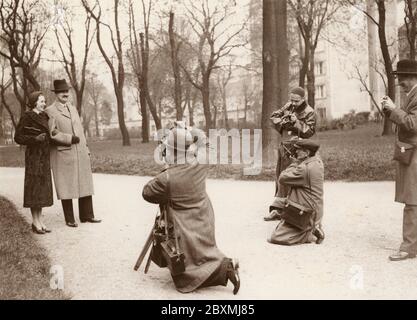 Press photographers. A couple has stopped during their walk to have their picture taken by a group of press photographers. 1930s Stock Photo