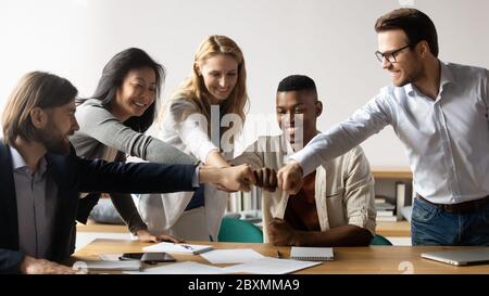 Five multiracial staff members show unity stacked hands in circle Stock Photo