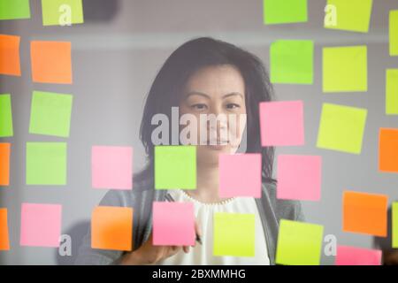 Mature asian coach makes presentation for staff using sticky notes Stock Photo