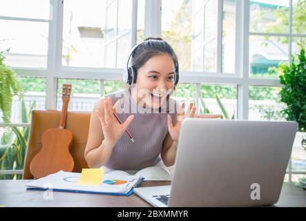Asian businesswomen are using notebook computers and wear headphones for online meetings and working from home. Stock Photo