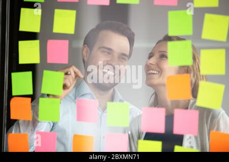 Colleagues attaching sticky notes working on to-do list Stock Photo
