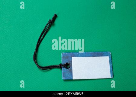 Blank tag tied with string. Price tag, gift tag, sale tag, address label isolated on green background. Stock Photo