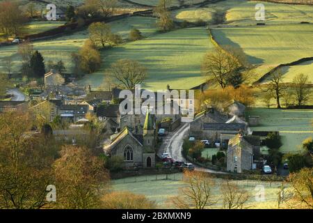 Burnsall (scenic Yorkshire Dales village) in valley, attractive cottages, country lane, green hillside fields (sunny winter morning) - England, GB, UK Stock Photo