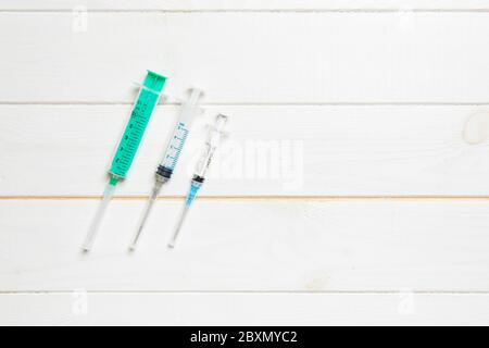 Top view of syringes of different sizes on wooden background. Medical equipment for injection concept with copy space. Stock Photo