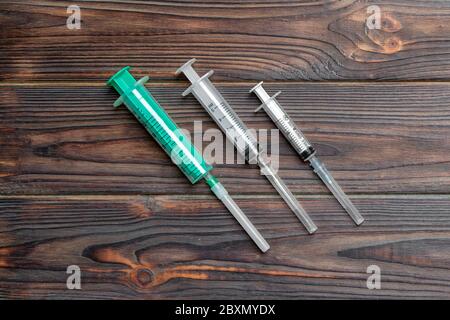 Top view of syringes of different sizes on wooden background. Medical equipment for injection concept with copy space. Stock Photo