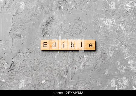 EDIBLE word written on wood block. EDIBLE text on cement table for your ...