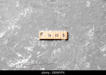 Fees word written on wood block. Fees text on cement table for your desing, Top view concept. Stock Photo