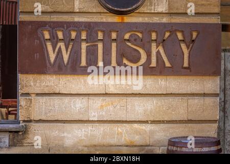 Old rusty whiskey sign at Oamaru in the South Island of New Zealand. Omaru is home to the steam punk. Stock Photo