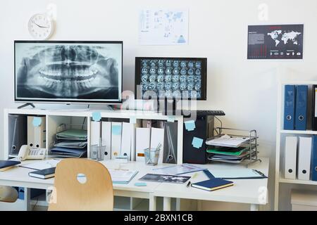Background image of modern computer equipment in clinic, focus on digital screen with CT and X ray scans at empty workplace in clinic, copy space Stock Photo