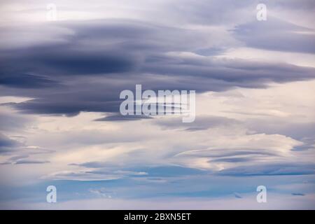 Gloomy layered clouds in cloudy, windy weather with blue gaps Stock Photo