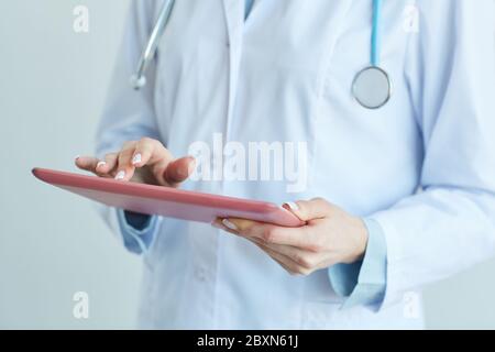 Mid section view of unrecognizable female doctor using digital tablet while working in clinic, close up with copy space Stock Photo