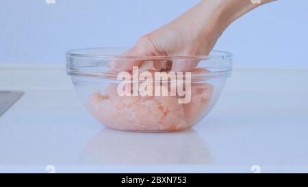 Girl is preparing minced meat. A female hand mixes the minced chicken and pork. Meat dishes Stock Photo