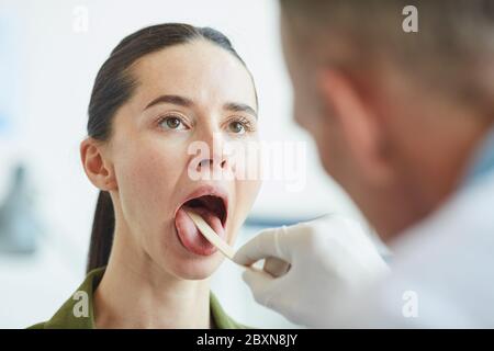 Close up portrait of young woman opening mouth during throat examination in clinic, copy space Stock Photo