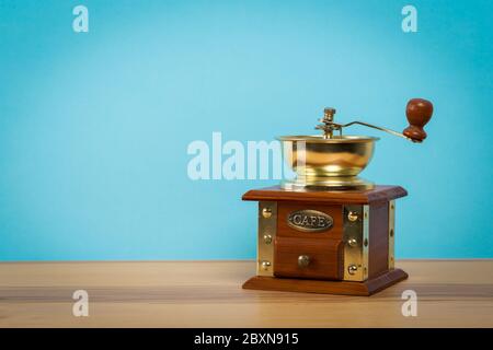 Vintage old manual coffee grinder on wooden table with color wall background Stock Photo