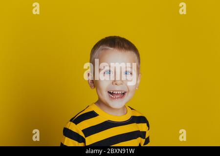 Portrait of an attractive smiling boy with in a striped sweater close-up, on a yellow background Stock Photo