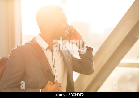 Joyful Businessman Talking On Cellphone Walking Through Airport Indoor Stock Photo
