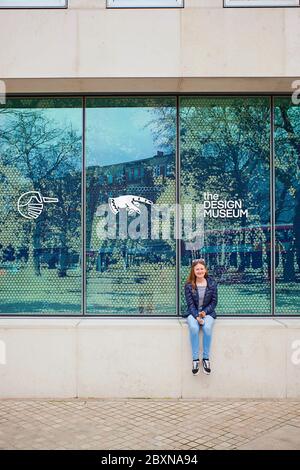 Young girl sitting outside The Design Museum,Kensington High St, London Stock Photo