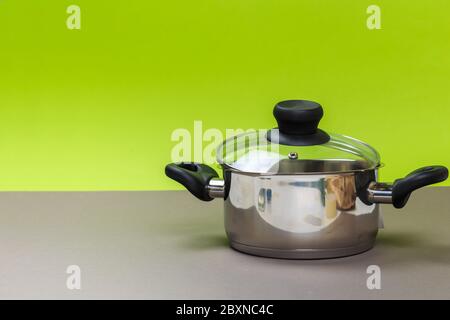 A new metal pan stands on a gray table and a green background. close-up Stock Photo