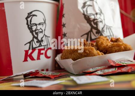 Kentucky Fried Chicken, KFC, fillets with packets of tomato ketchup on a table top and bucket and bag with the company logo and trademark. Stock Photo