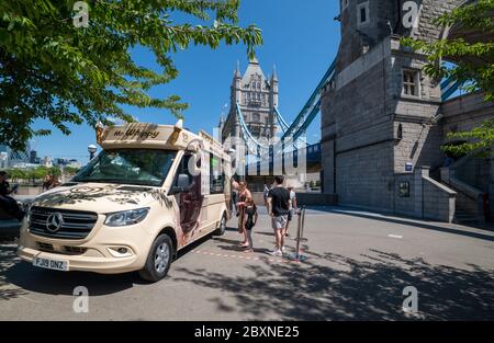 People buying drinks and ice cream from a ice cream seller with his van parked by Tower Bridge. Stock Photo