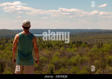 Rear View Of Man Sitting On Rock Over Landscape. Stock Photo