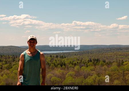 Rear View Of Man Sitting On Rock Over Landscape. Stock Photo