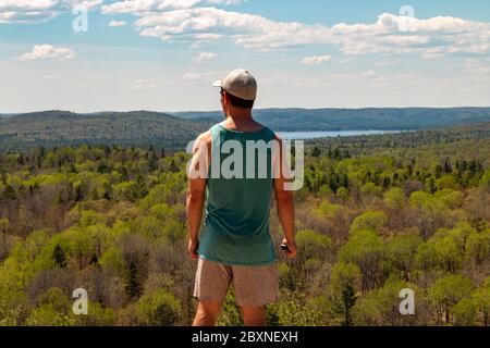 Rear View Of Man Sitting On Rock Over Landscape. Stock Photo