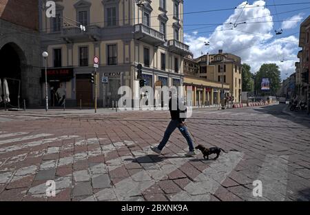 A man walking and his dog walking on the emptiness of the city, during the lockdown due to the Covid-19 emergency, in Milan, Italy. Stock Photo