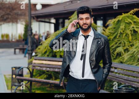 Bearded Indian man on the street using the application in his smartphone. Stock Photo