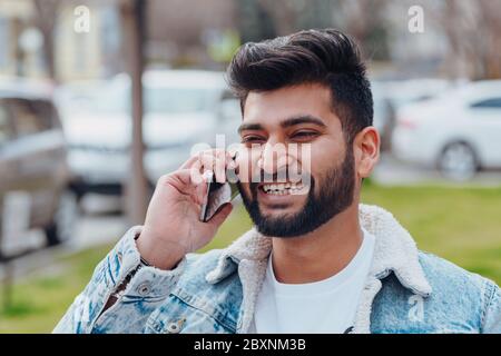 Bearded Indian man on the street using the application in his smartphone. Stock Photo