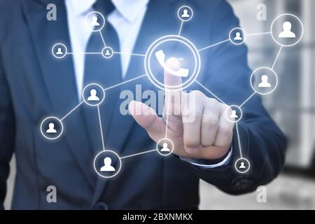 Businessman hand press telephone button icon on virtual screen for network connection. Idea for contact communication in business. Stock Photo